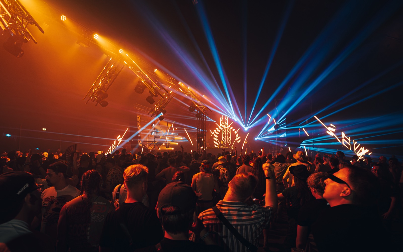 Lightshow mit orangen und blauen Lichtstrahlen über dem Publikum